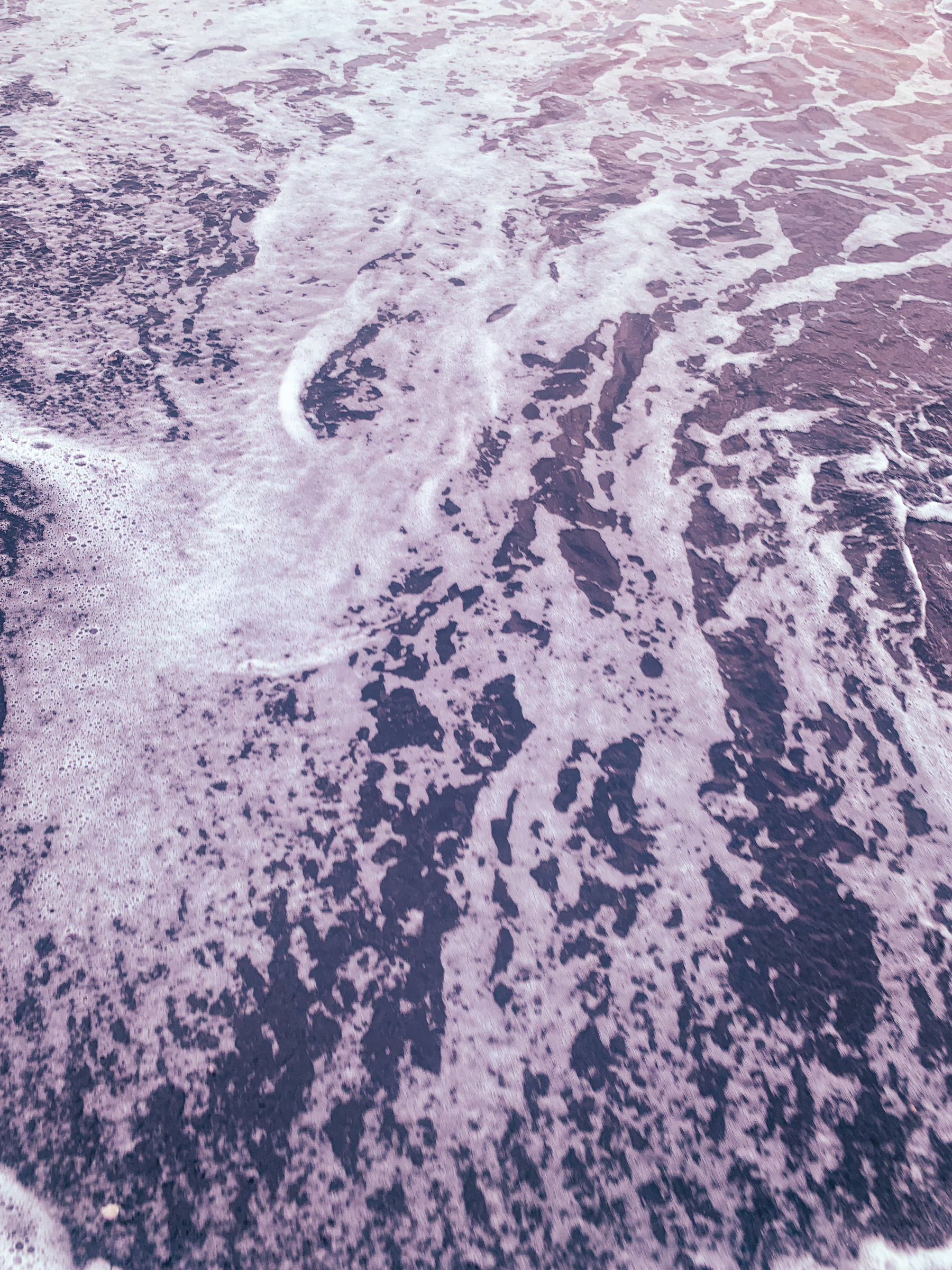 photo of dusky purple foamy sea water swirling
